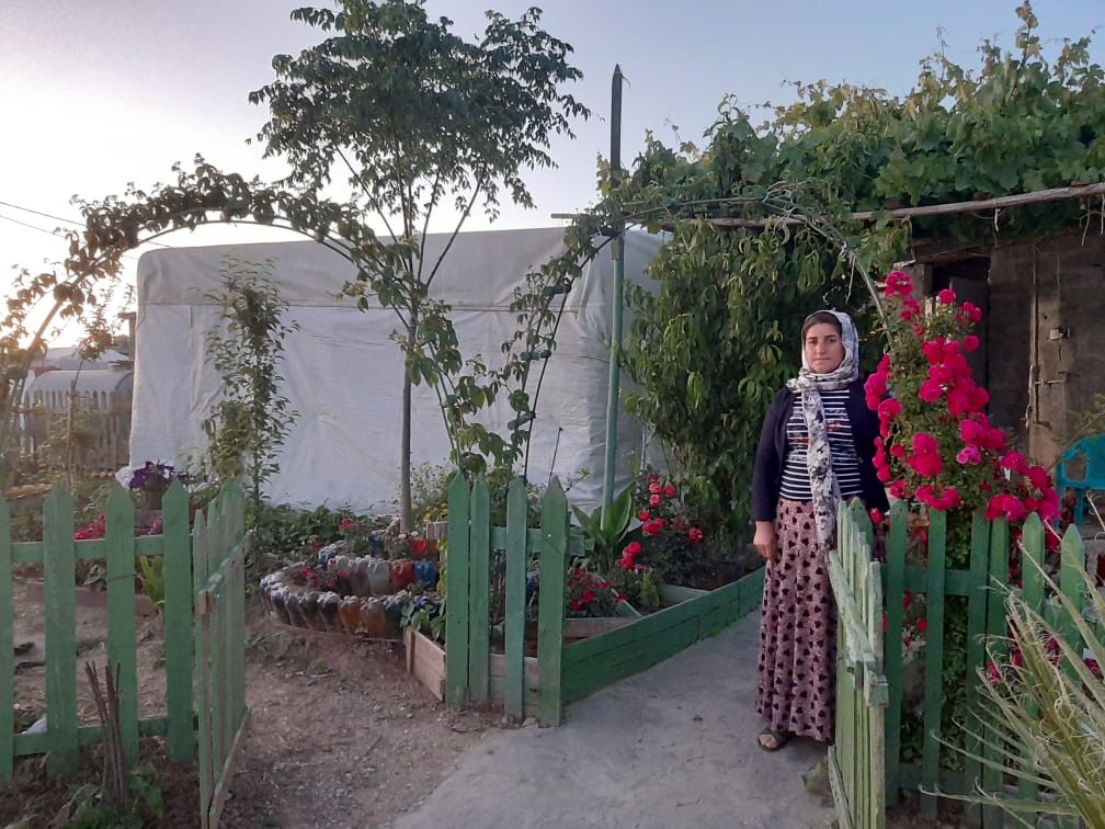 Women at garden gate with red flowers